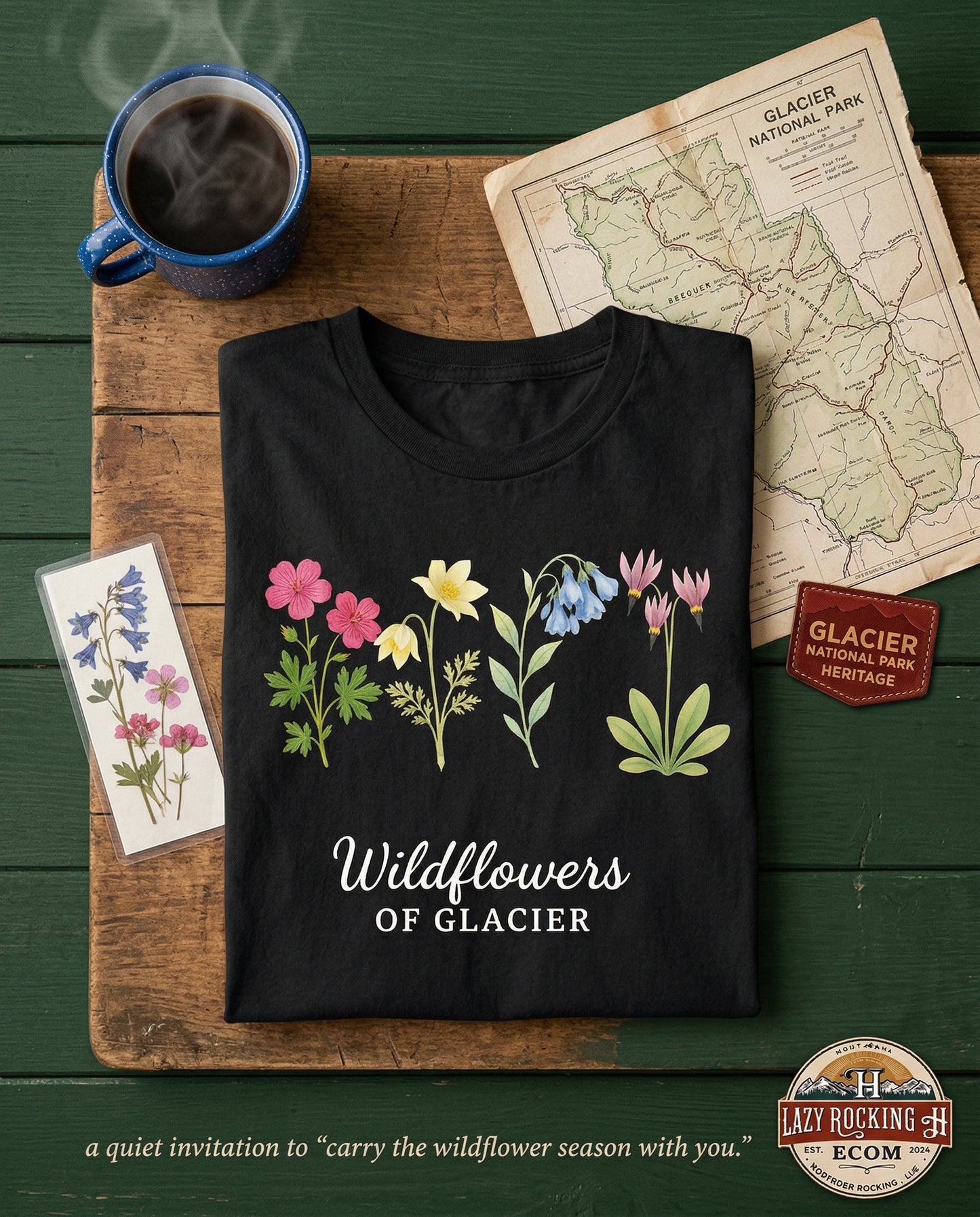 Black t-shirt with floral design and text on a wooden surface with coffee and map.